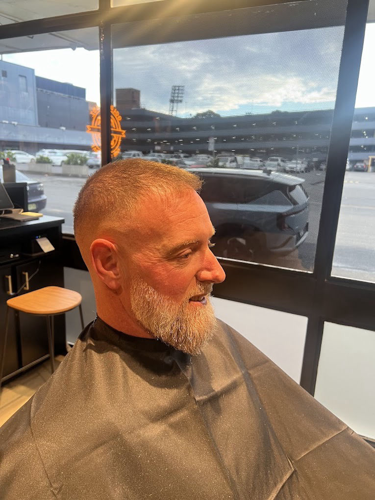 Barber at Golden Fadz Gosford finishing a client's beard trim by the window