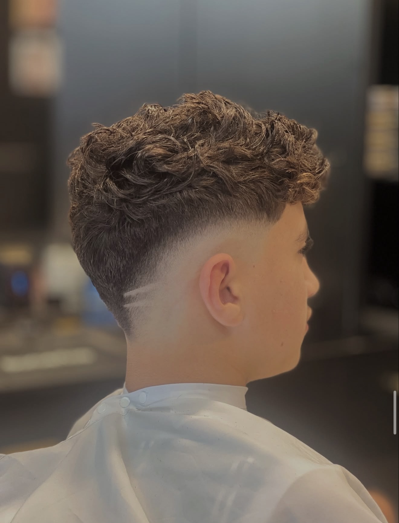 Curly top with a mid skin fade and hair design line at Golden Fadz Gosford