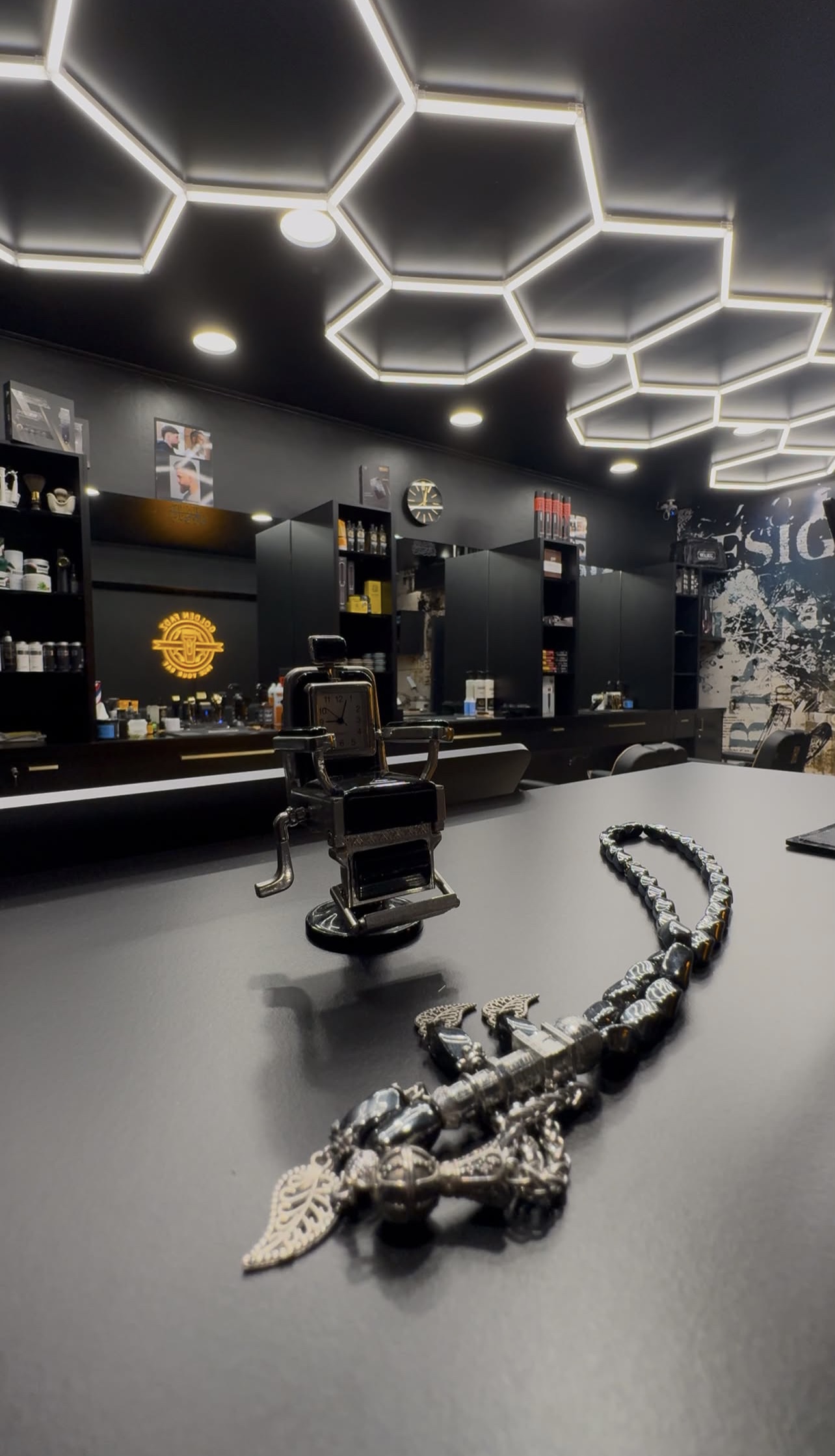 Inside Golden Fadz barber shop, Gosford — hexagon ceiling lighting, black fit-out and the gold neon logo behind the counter